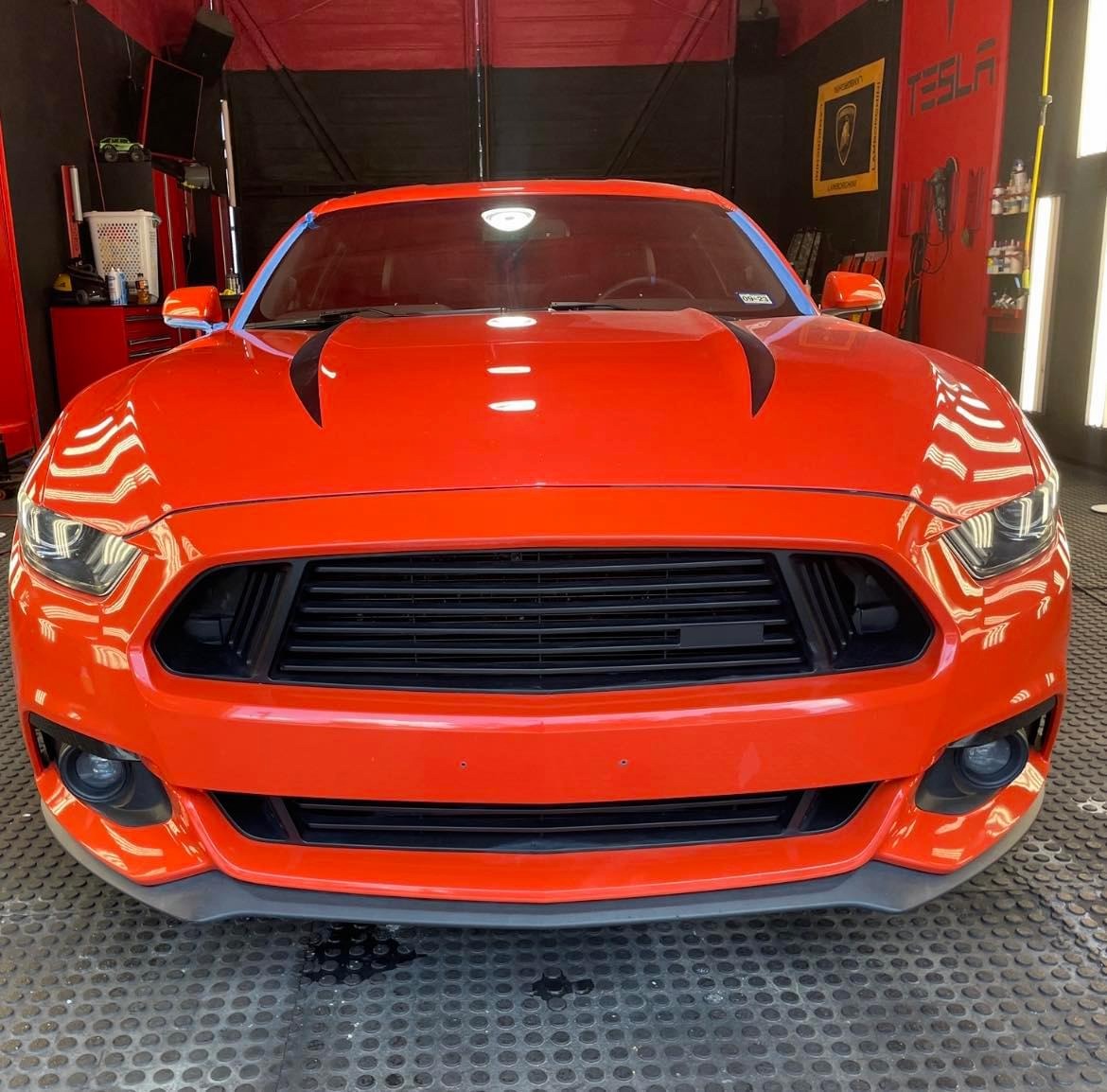 An orange Ford Mustang head-on in the detail bay